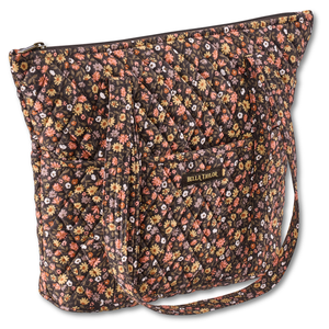 Stride Tote front view featuring quilted floral fabric in espresso brown, golden tan, soft ivory, and dusty mauve with top zip closure, and 10 total pockets.